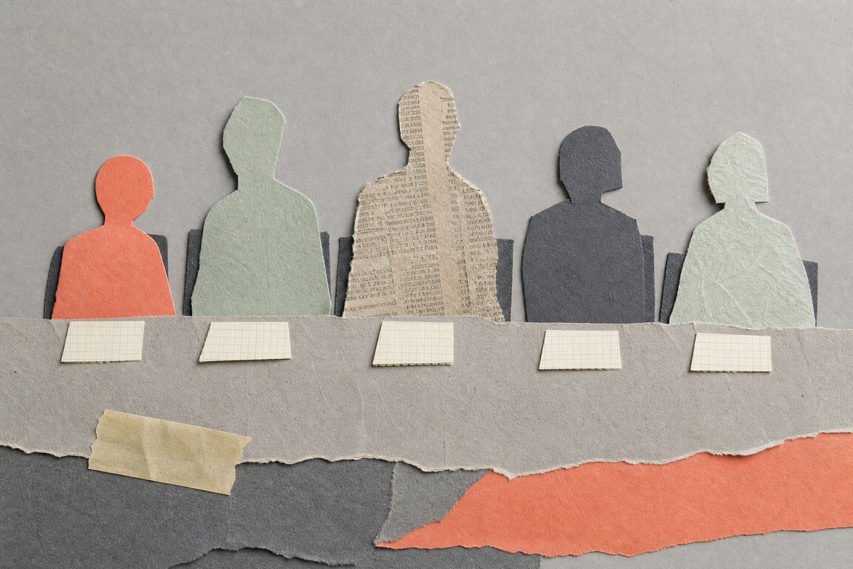 Paper collage of five cut-paper figures seated behind a long torn-paper table